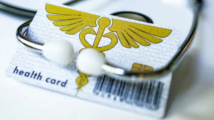 Eine Gesundheitskarte liegt unter einem Stethoskop