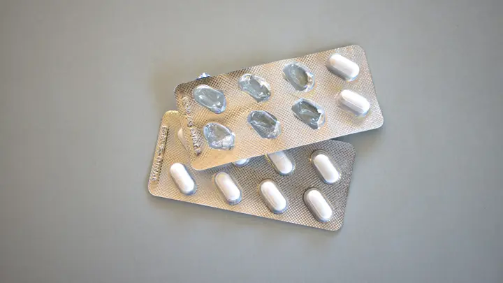 Zwei Blisterstreifen mit weißen Tabletten auf grauem Untergrund