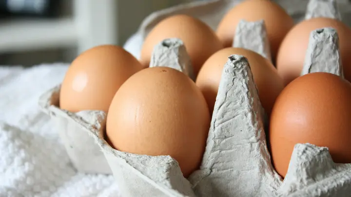 Braune Hühnereier in einem Eierkarton auf einem weißen Tuch