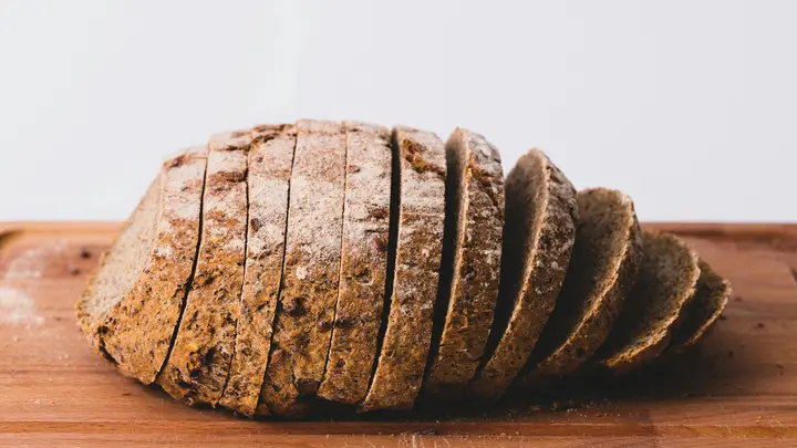 Aufgeschnittenes Vollkornbrot auf einem Holzbrett vor hellem Hintergrund
