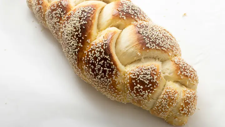 Geflochtenes Hefebrot mit Sesam auf hellem Backpapier