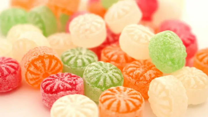 Bunte Bonbons in Rosa, Grün und Weiß auf hellem Untergrund